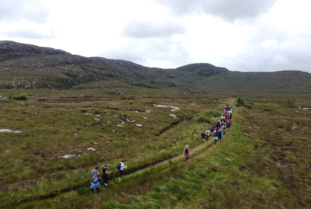 Large group walking along a trail across bogland in Donegal